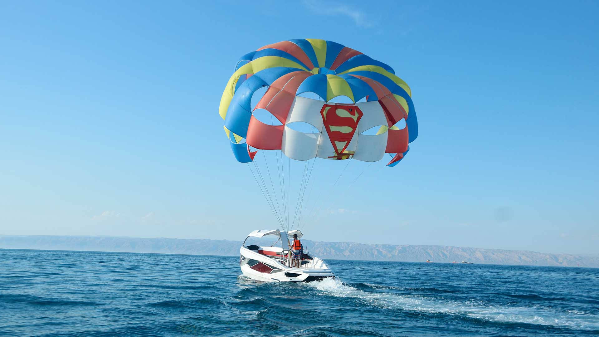 Parasailing Adventure In Prism Blue Waters Background