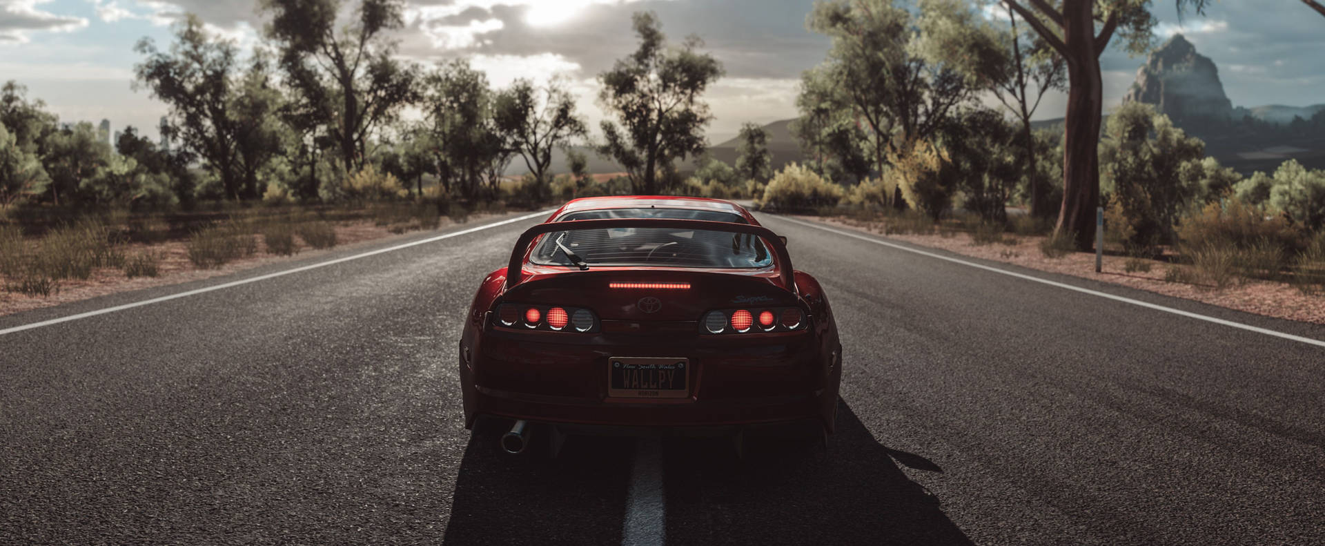 Parked Red Toyota Supra At Road Background