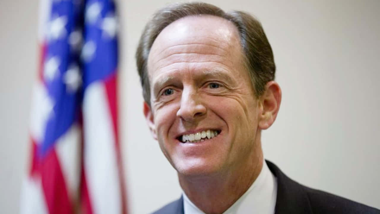 Pat Toomey Smiling With Flag Background