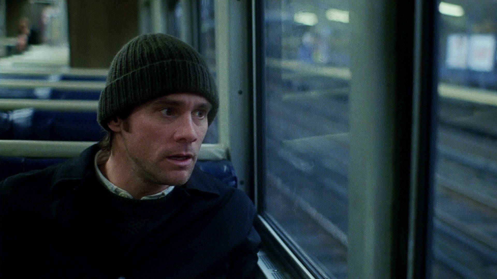 Pensive Jim Carrey Looking Out A Window Background