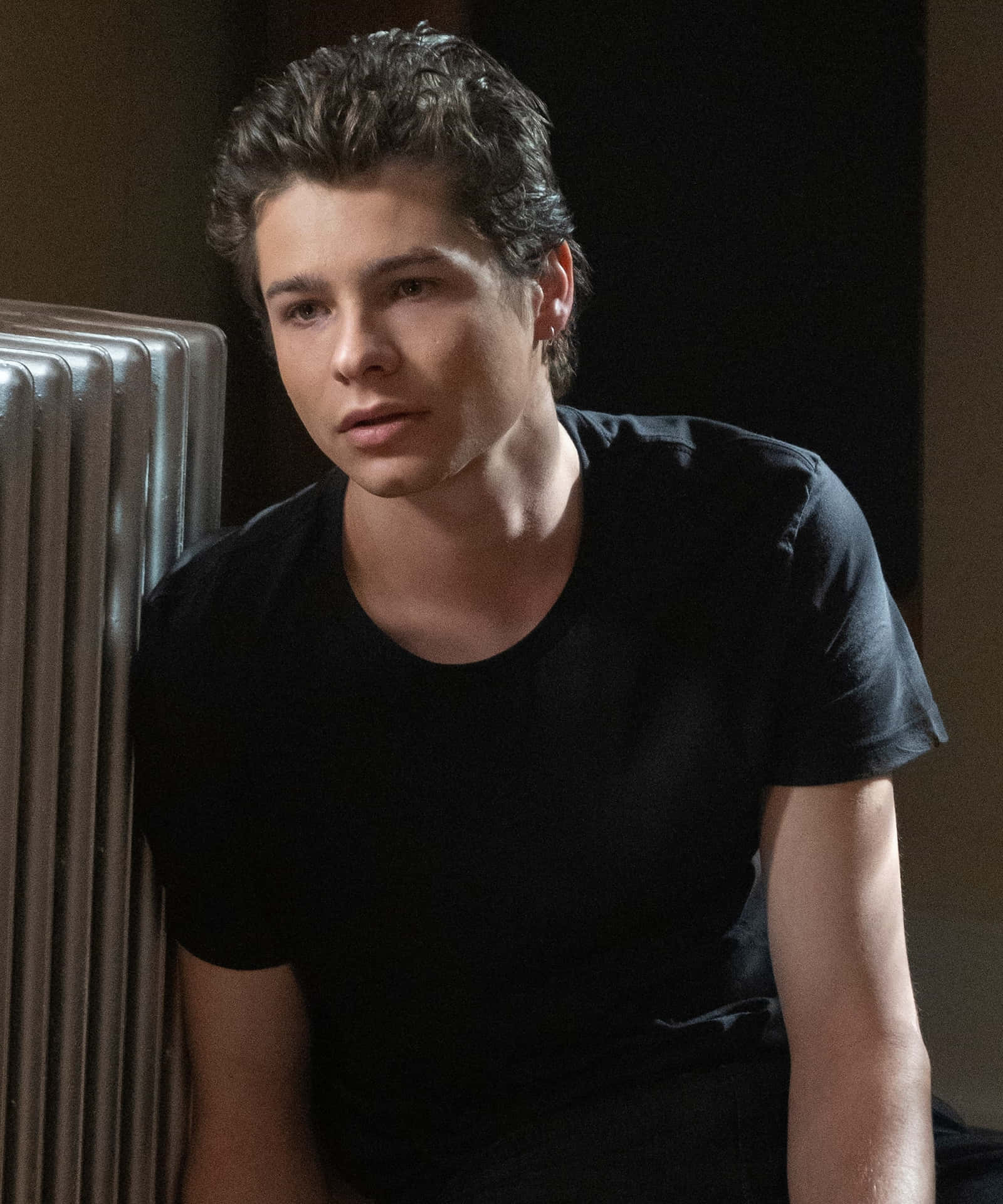 Pensive Young Man Leaningon Radiator Background