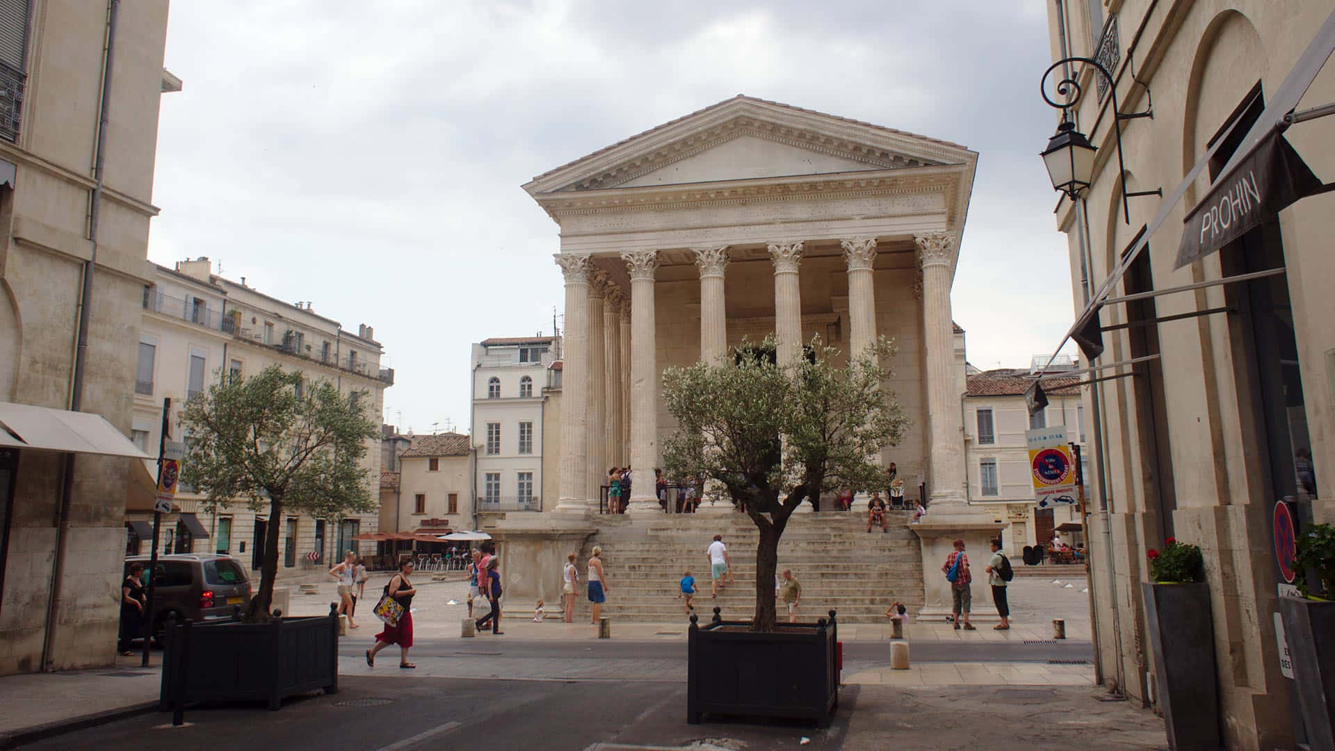 People Walking By Maison Carrée Background