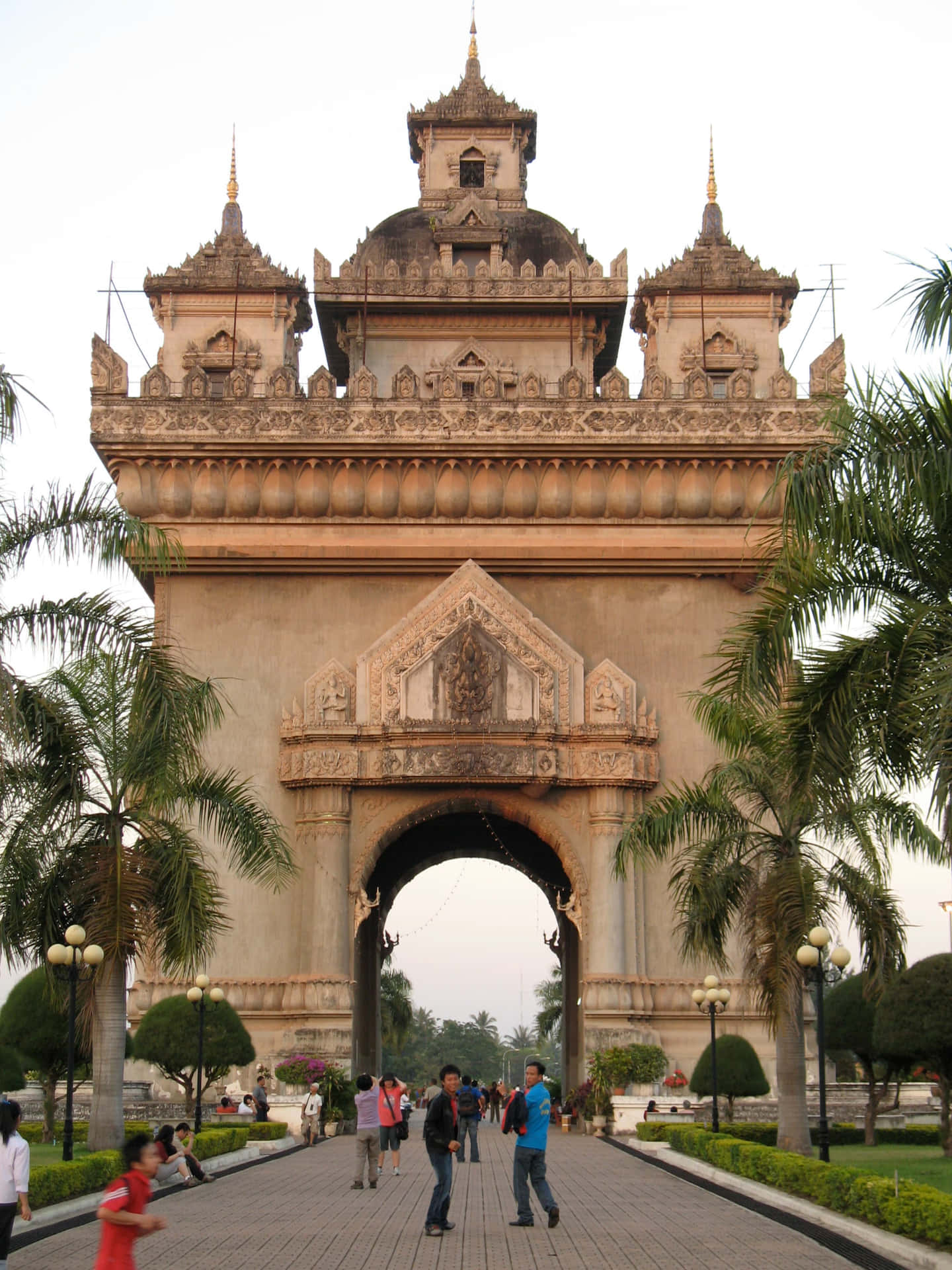People Walking Through Patuxai Monument Background