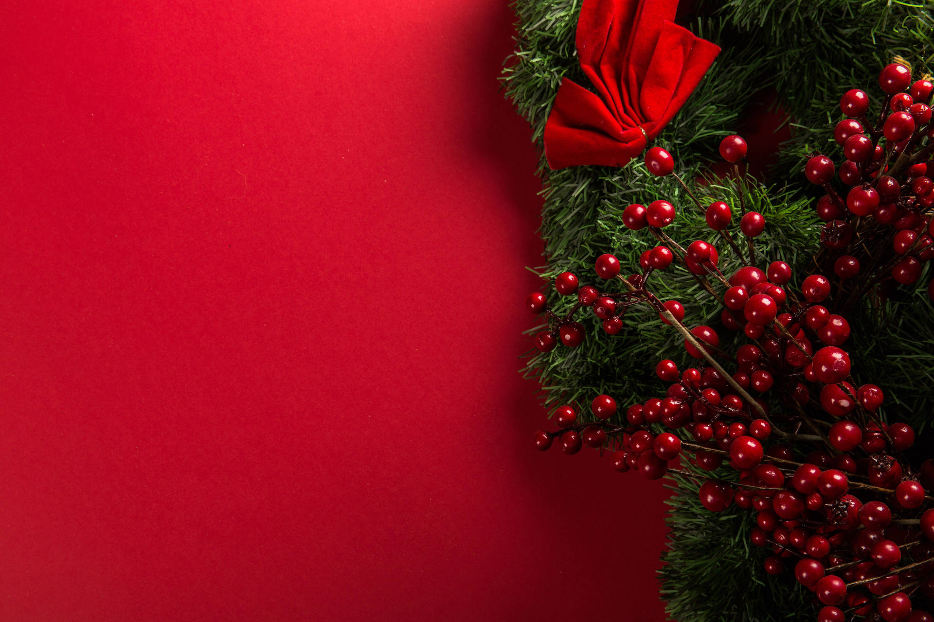 Perfect For The Holiday Season: A Red Christmas Wreath Set Against A White Wall Background