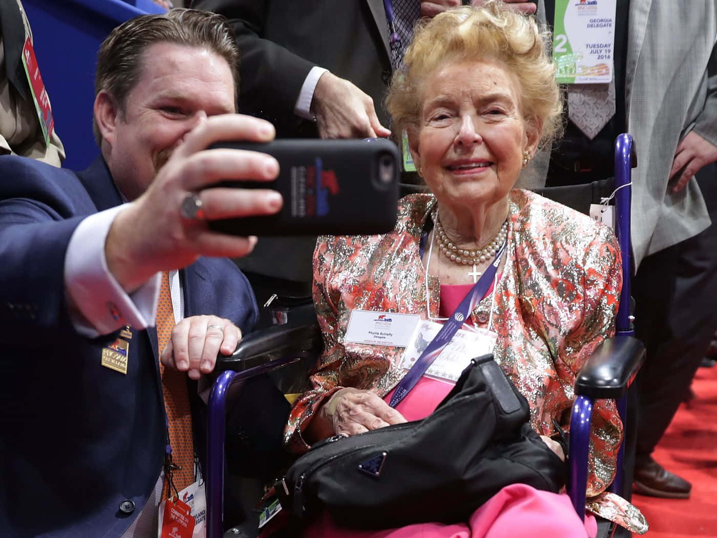 Phyllis Schlafly Posing For A Selfie With A Supporter Background