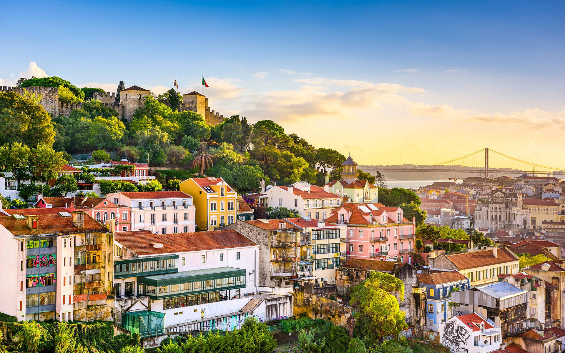 Picturesque View Of Hillside Homes Amidst Lush Greenery In Lisbon Background