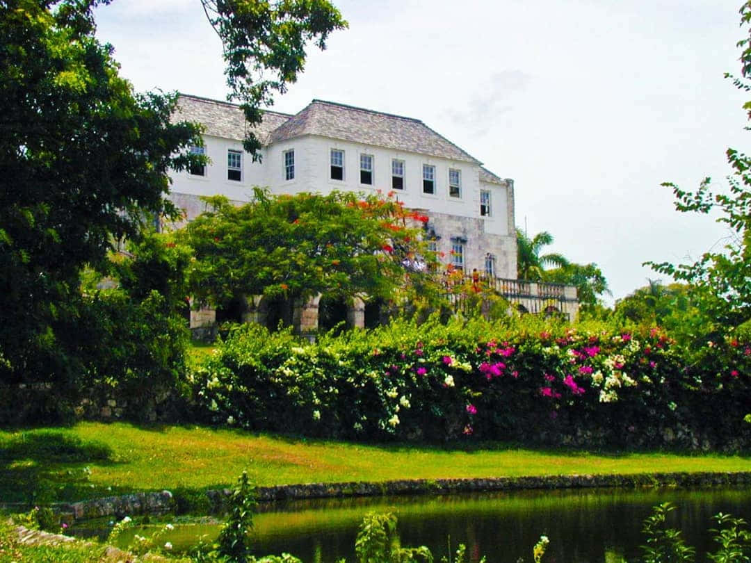 Picturesque View Of Rose Hall Great House Surrounded By Stunning Flora Background