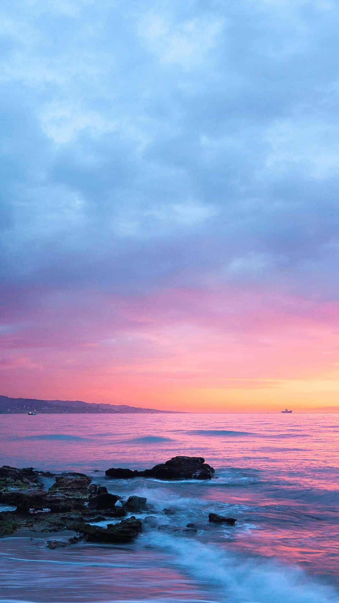 Pink Beach Sunset With Waves Hitting Rocks Background