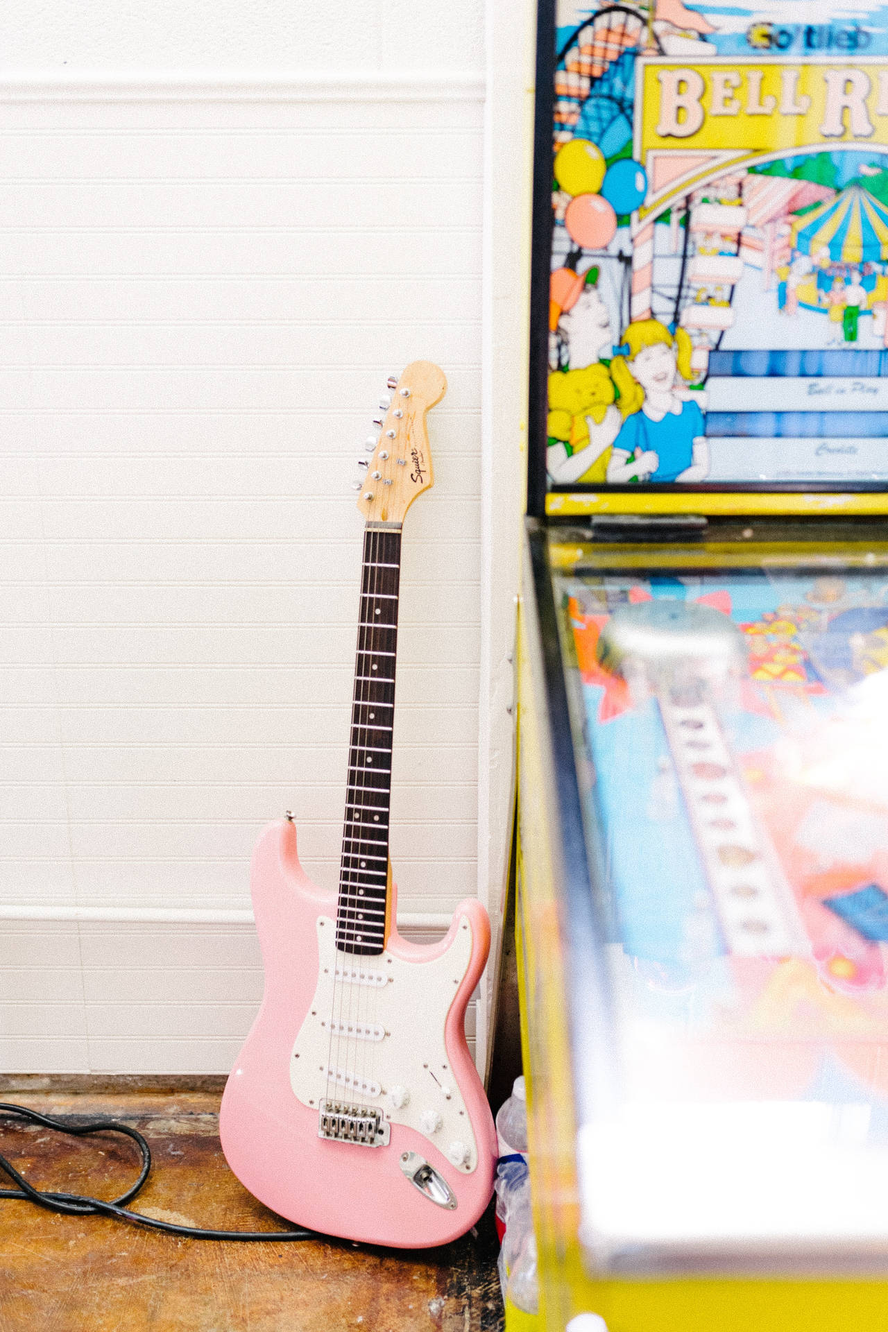 Pink Electric Guitar Besides Pinball Background