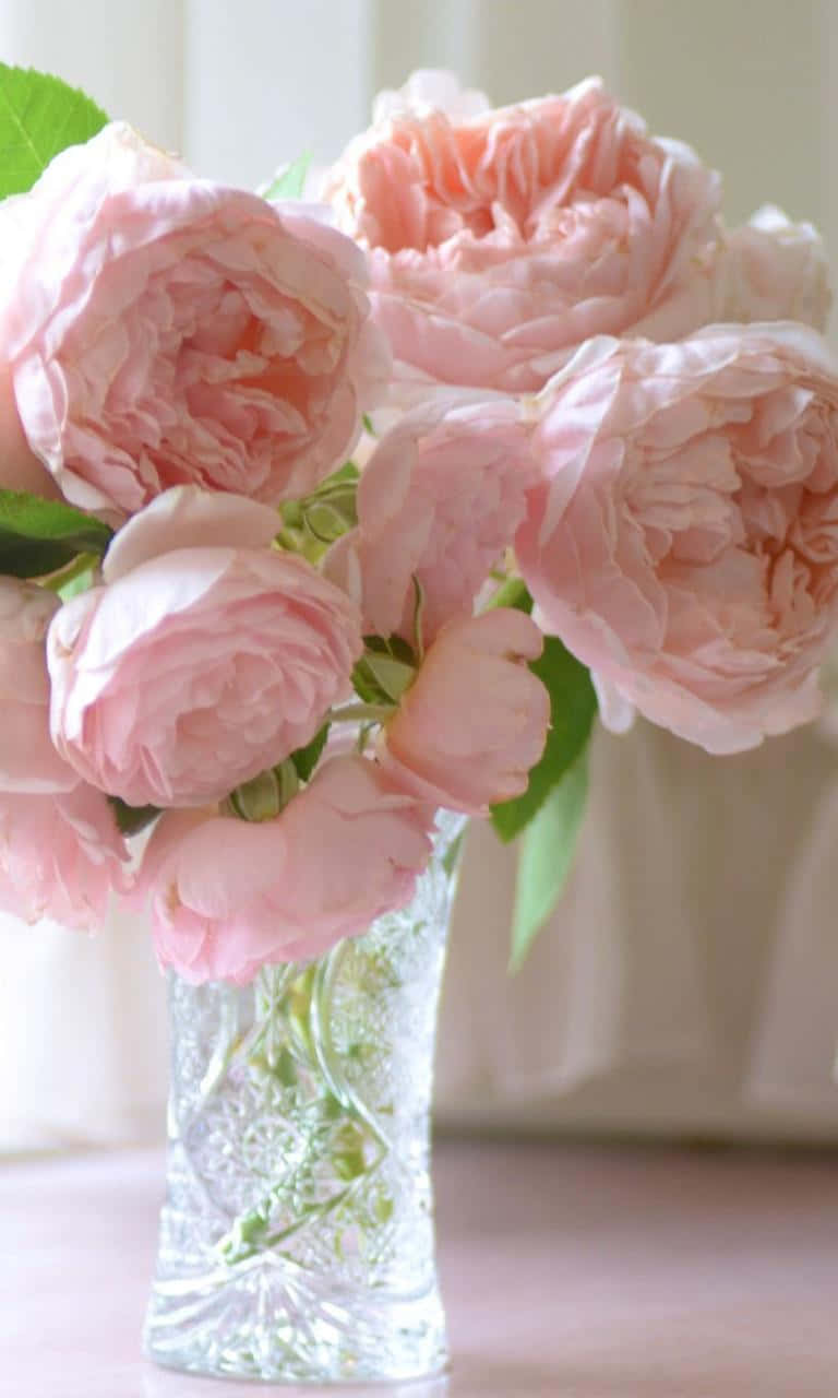 Pink Roses In A Glass Vase On A Table Background