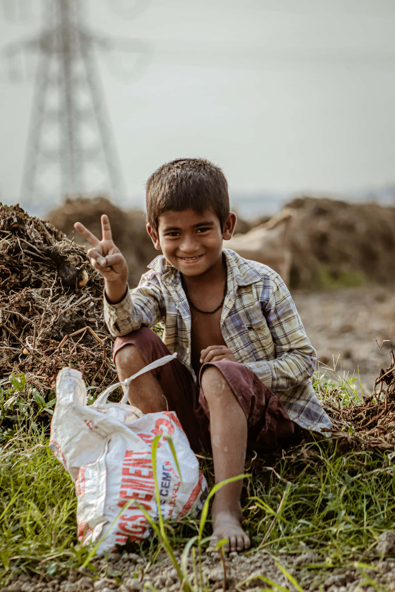 Poor Boy Sitting Down Doing A Peace Sign