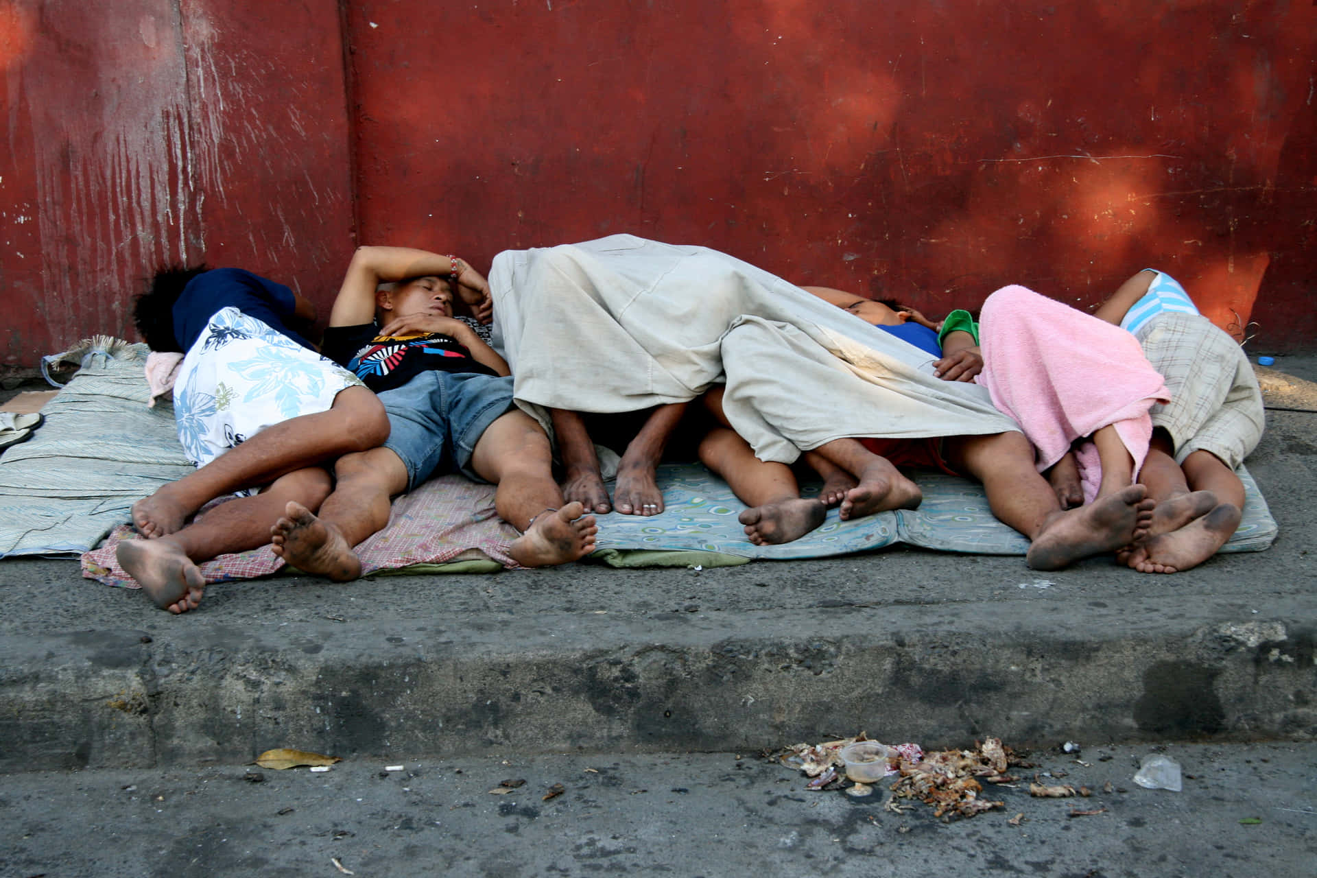 Poor Family Sleeping Beside The Street Background