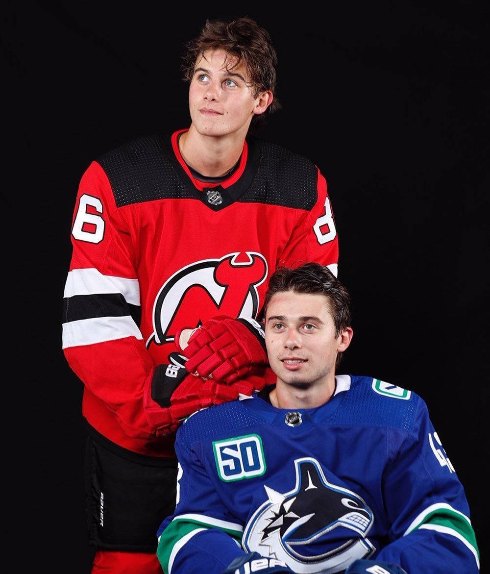 Portrait Of Quinn Hughes Posing With Brother Jack Hughes From New Jersey Devils Background