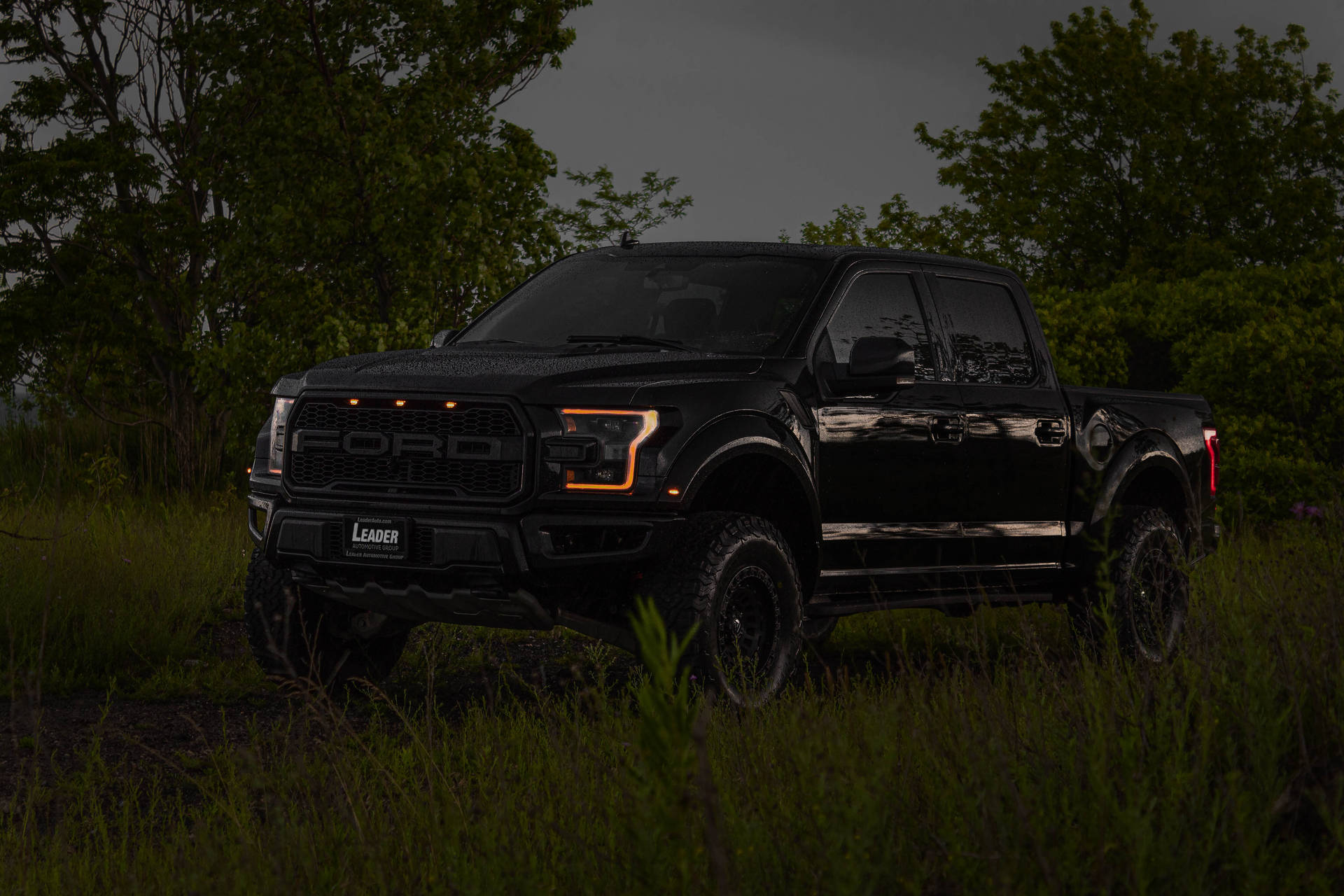 Powerful Ford Raptor With Vibrant Orange Headlights Shining In The Dark Background