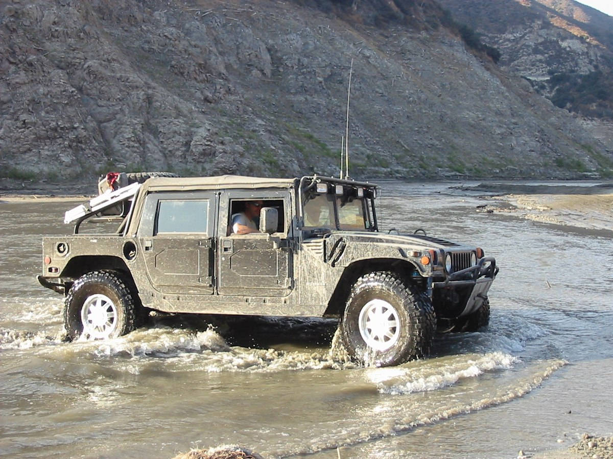 Powerful Hummer Making Its Way Through A River Background