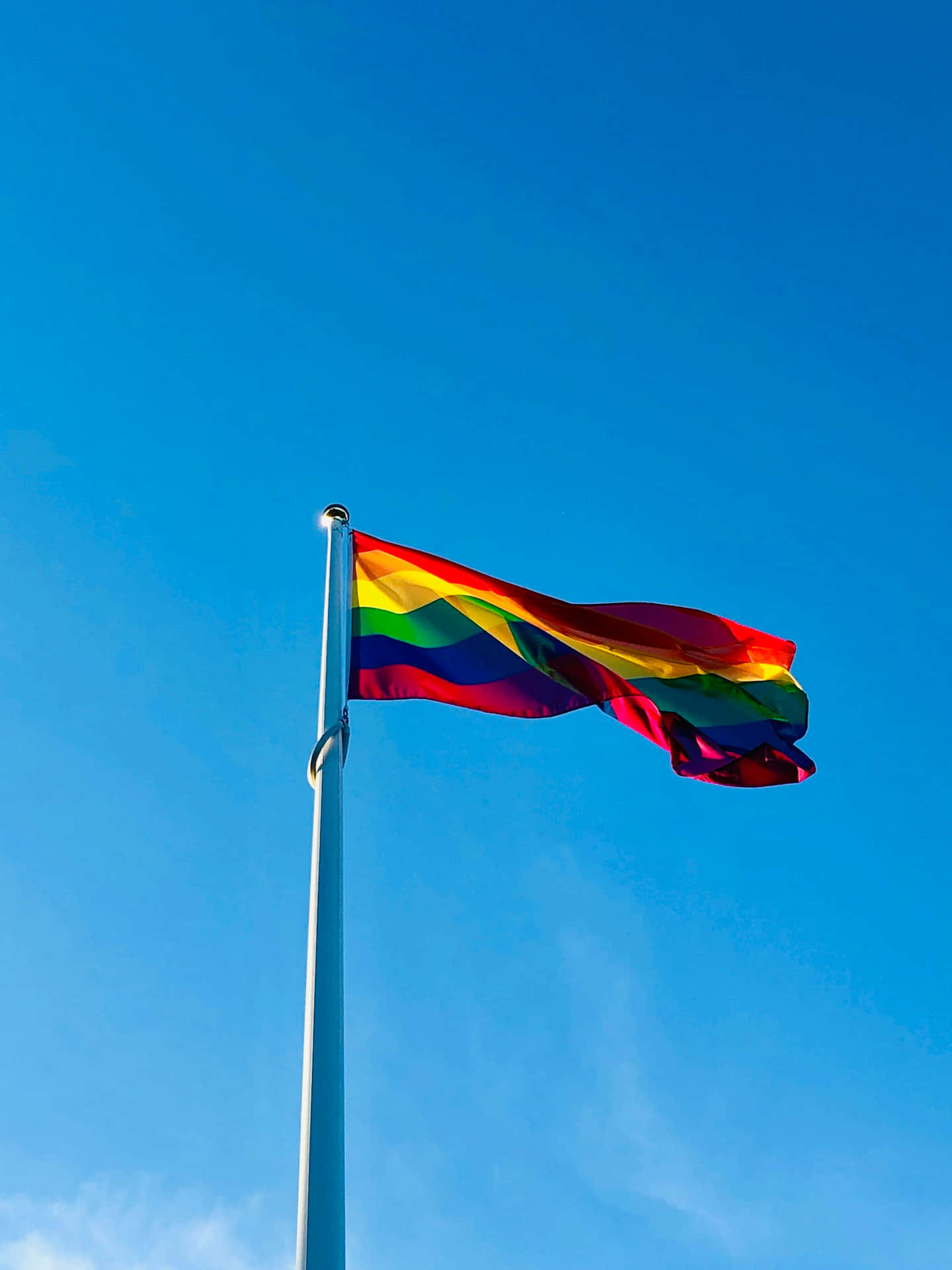 Pride Flag Waving Against Blue Sky