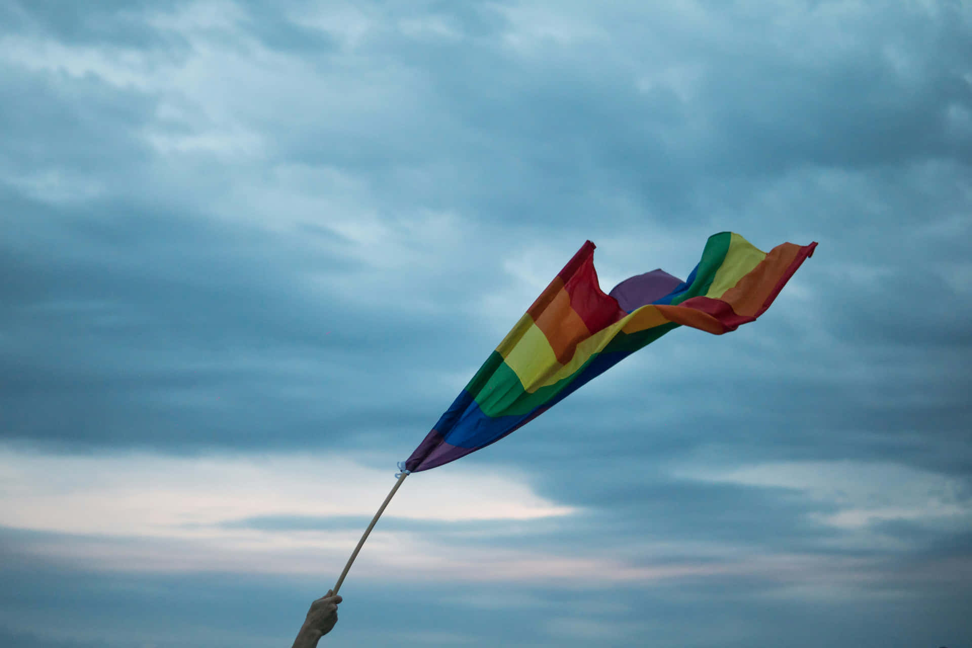 Pride Flag Waving Against Cloudy Sky Background