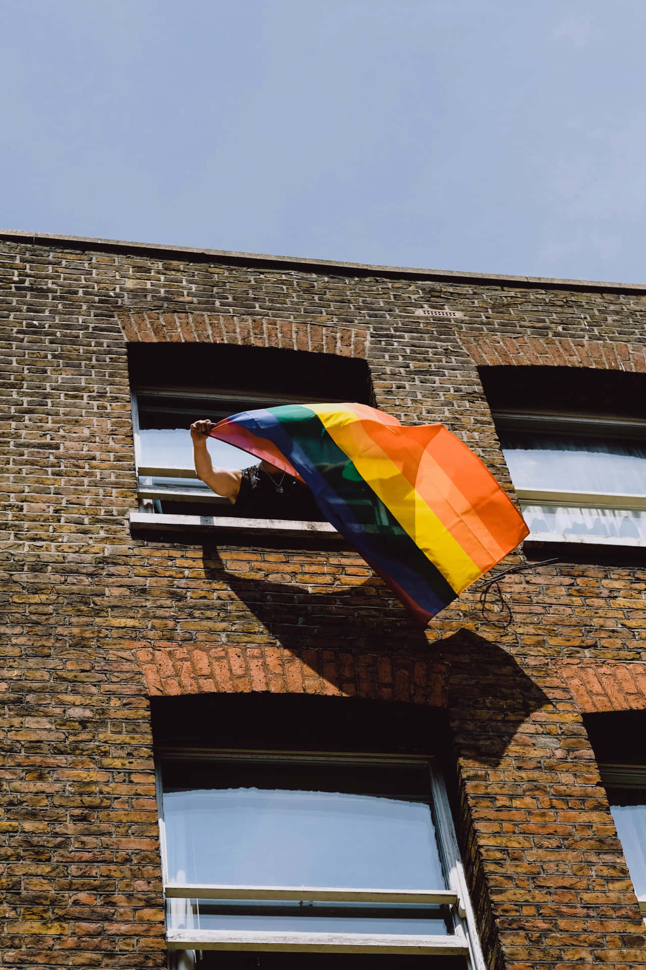 Pride_ Flag_ Waving_from_ Window Background