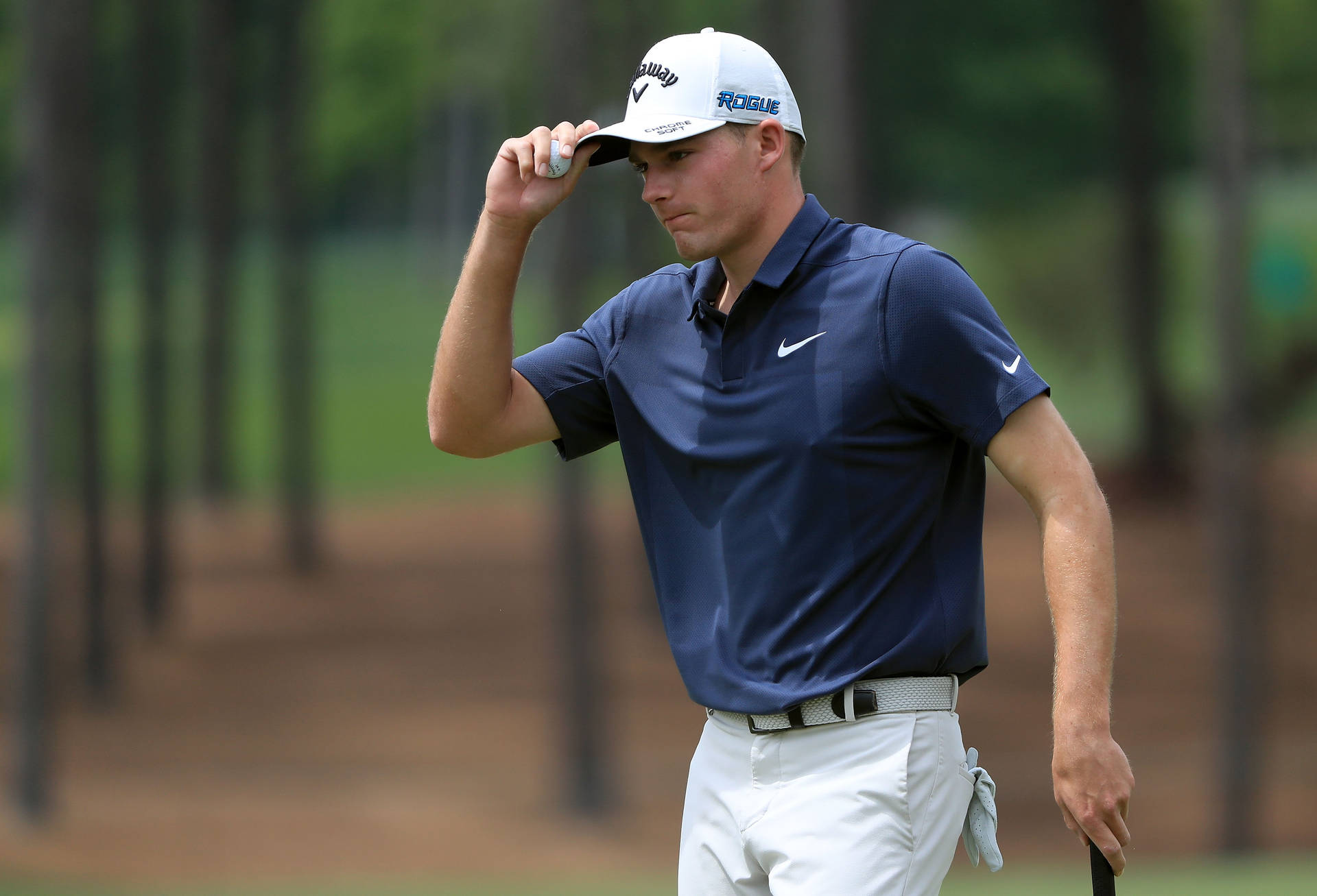 Pro Golfer Aaron Wise Holding His Cap In A Contemplative Moment Background