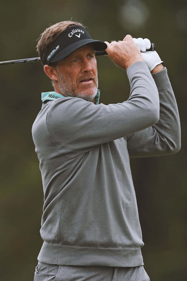 Pro Golfer Stuart Appleby Donning A Stylish Gray Sweater Background