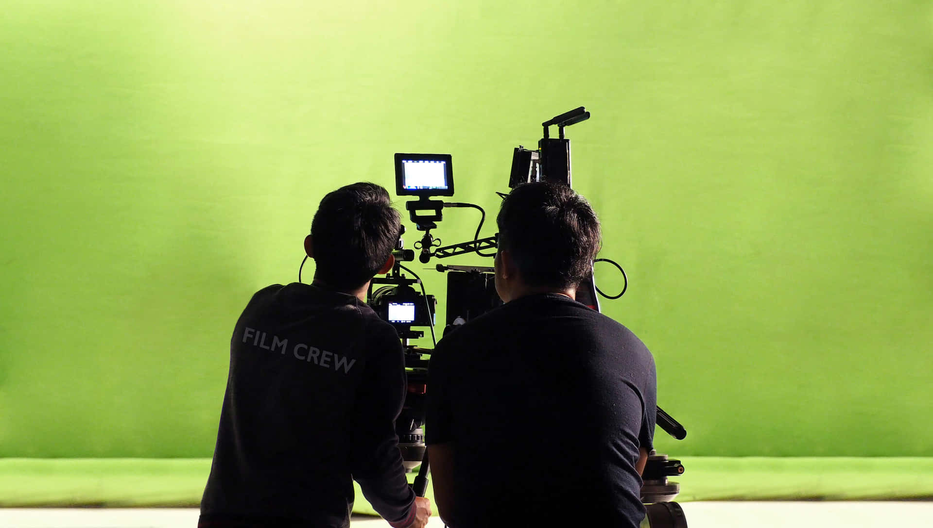 Professional Cameramen At Work In A Green Screen Studio