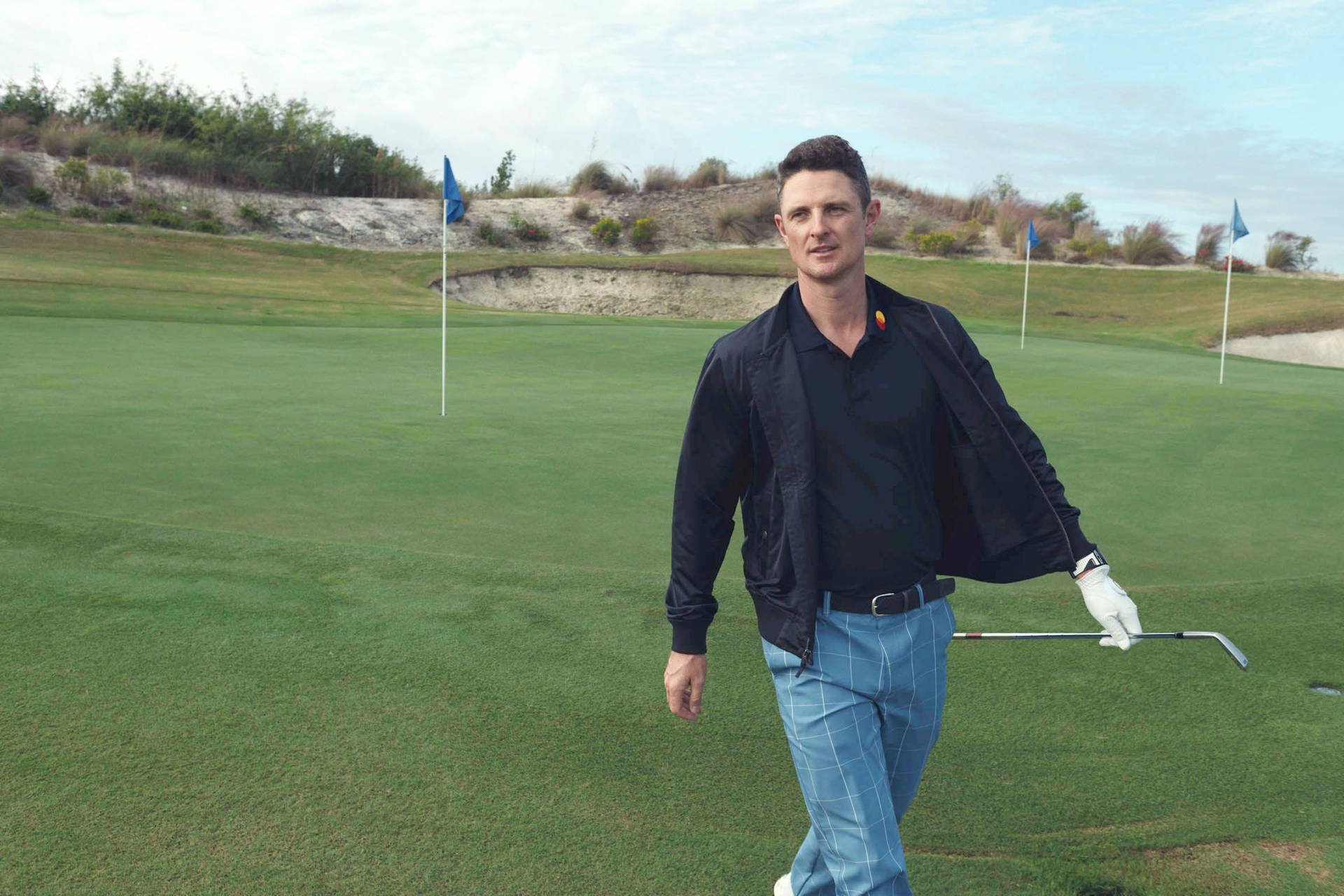 Professional Golfer Justin Rose Confidently Walking On A Golf Course.