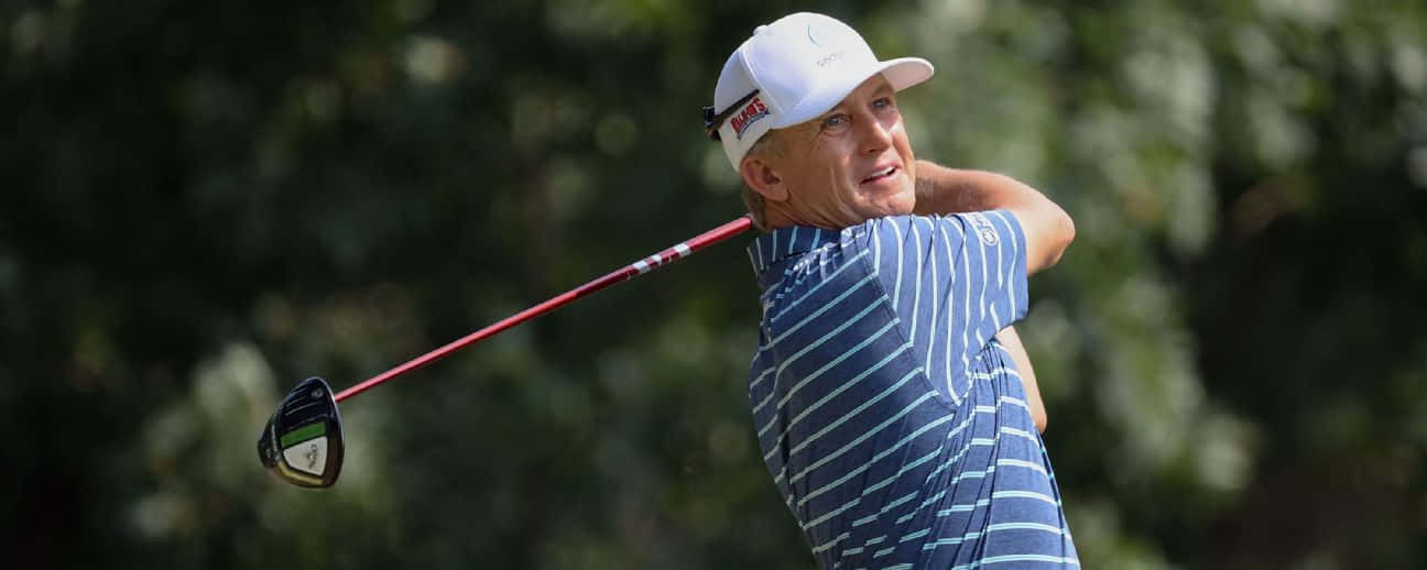 Professional Golfer Ken Duke In The Midst Of An Upper Swing At The Golf Course Background
