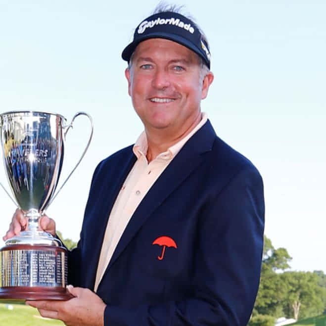 Professional Golfer Ken Duke Strikes A Classic Pose On The Green. Background