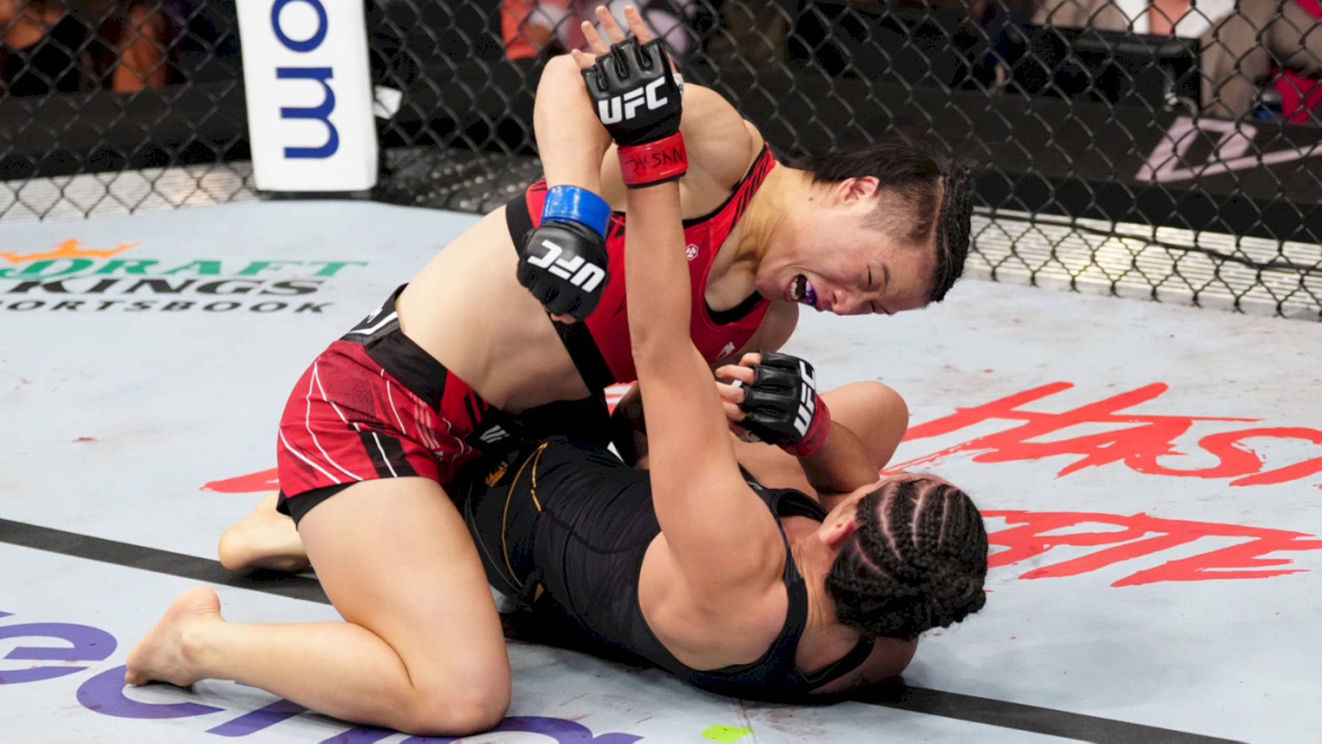 Professional Mma Fighter, Zhang Weili, In Intense Fighting Action Against An Opponent. Background