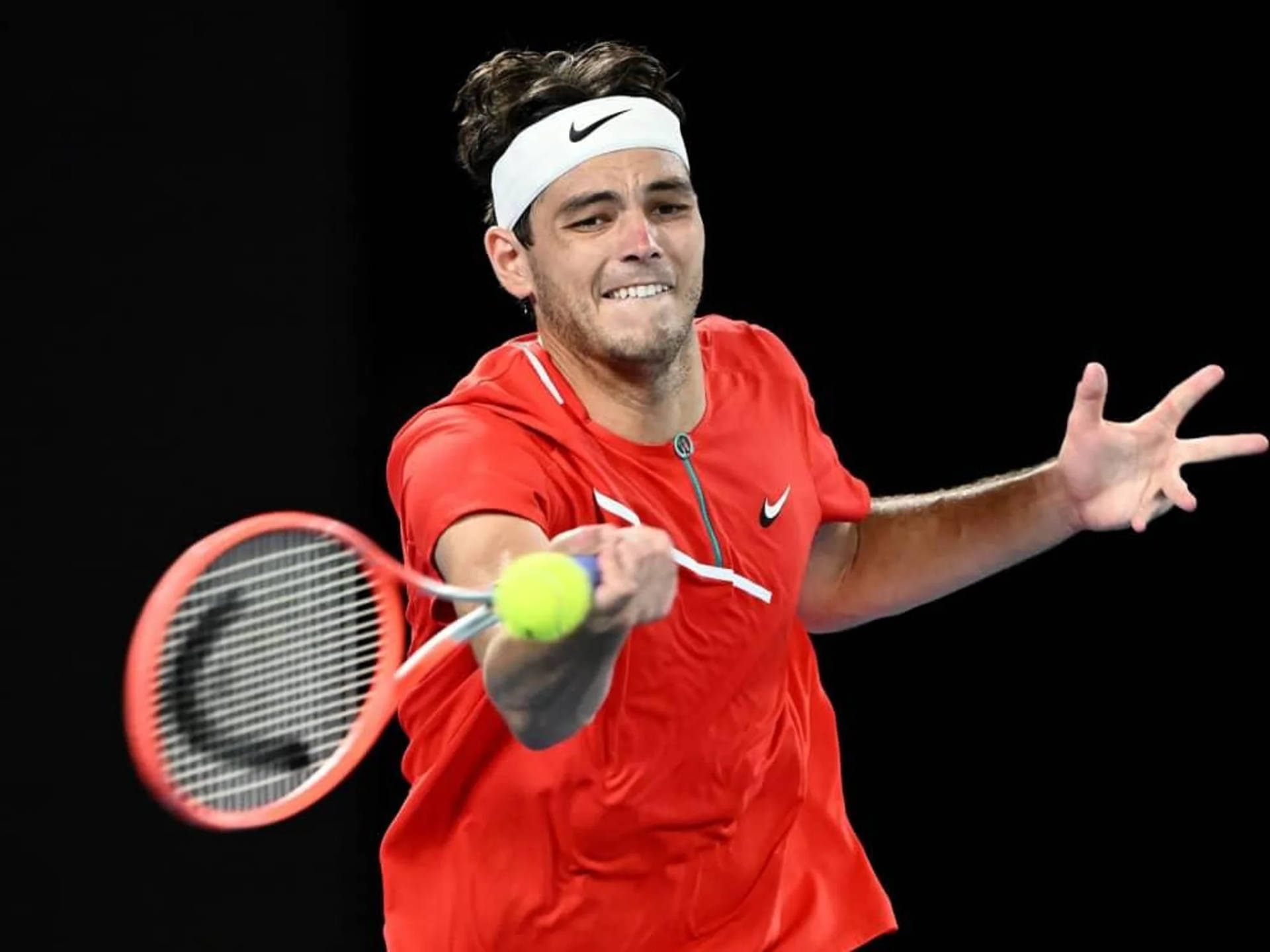 Professional Tennis Player Taylor Fritz Executing A Powerful Forehand Shot. Background