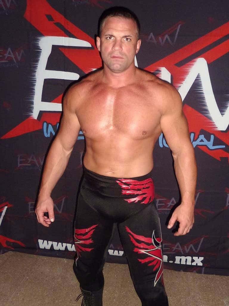 Professional Wrestler Posing Red Black Attire Background