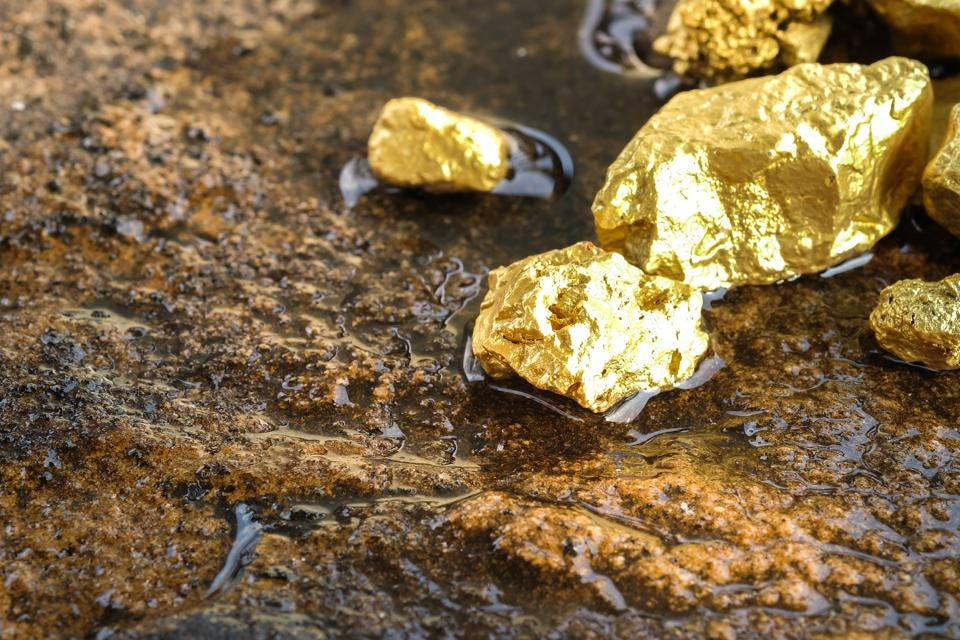 Pure Gold Nuggets On The Wet Ground Background