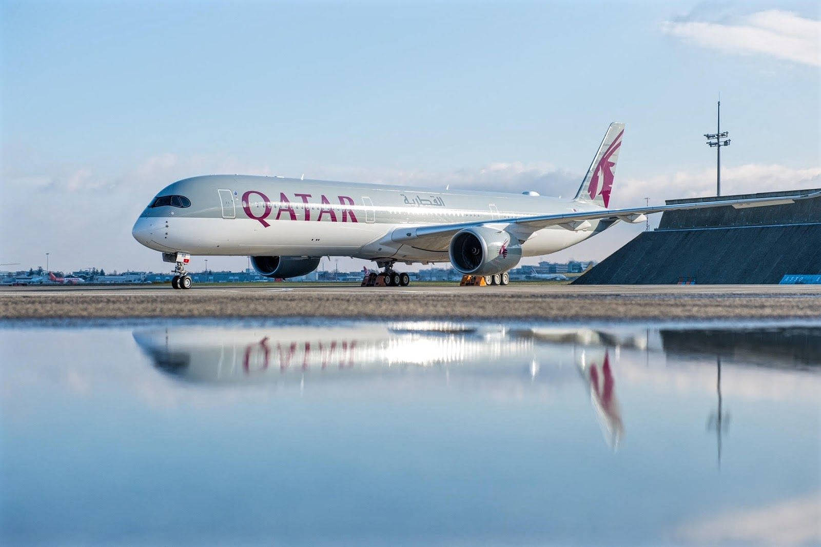 Qatar Airways Plane By A Pool Of Calm Water Background