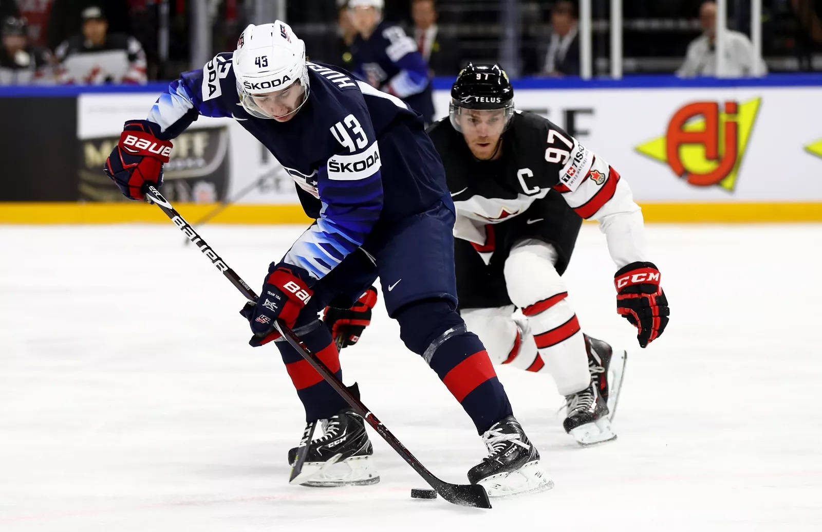 Quinn Hughes Dribbling Hockey Puck In Front Of Player From Team Canada Background