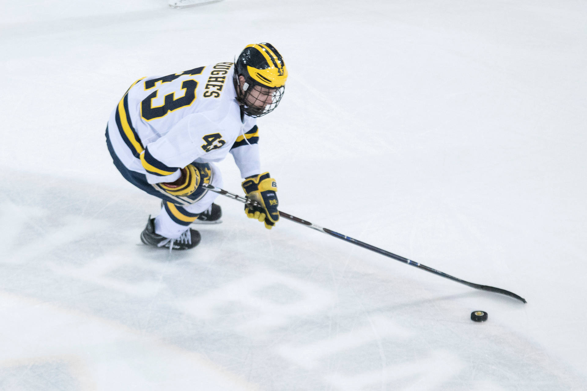 Quinn Hughes Leaning Forward While Dribbling Hockey Puck Background