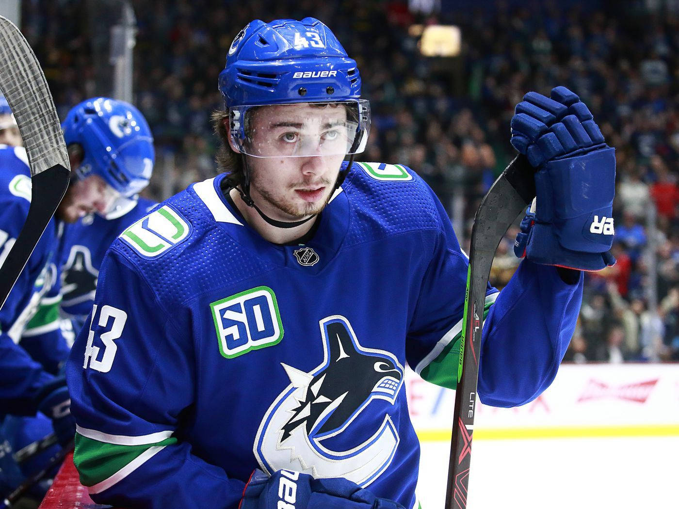 Quinn Hughes Looking Up While Holding Hockey Stick Blade Background