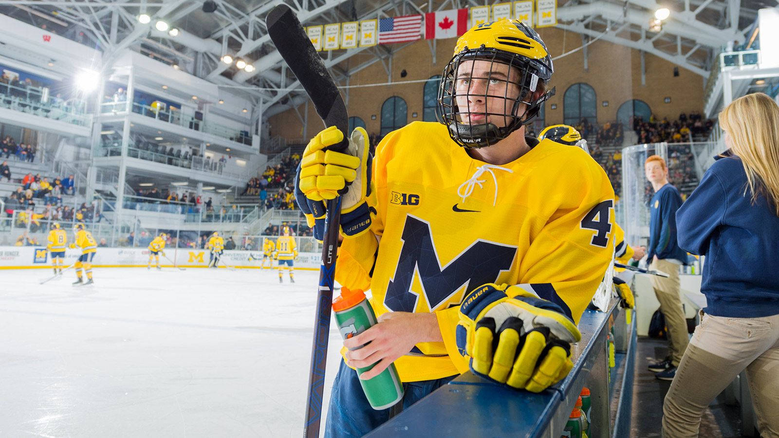 Quinn Hughes Resting During Warm-up Holding Tumbler And Hockey Stick Background