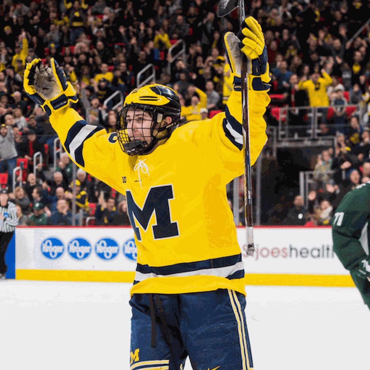 Quinn Hughes With Both Hands In The Air And Holding Hockey Stick Background