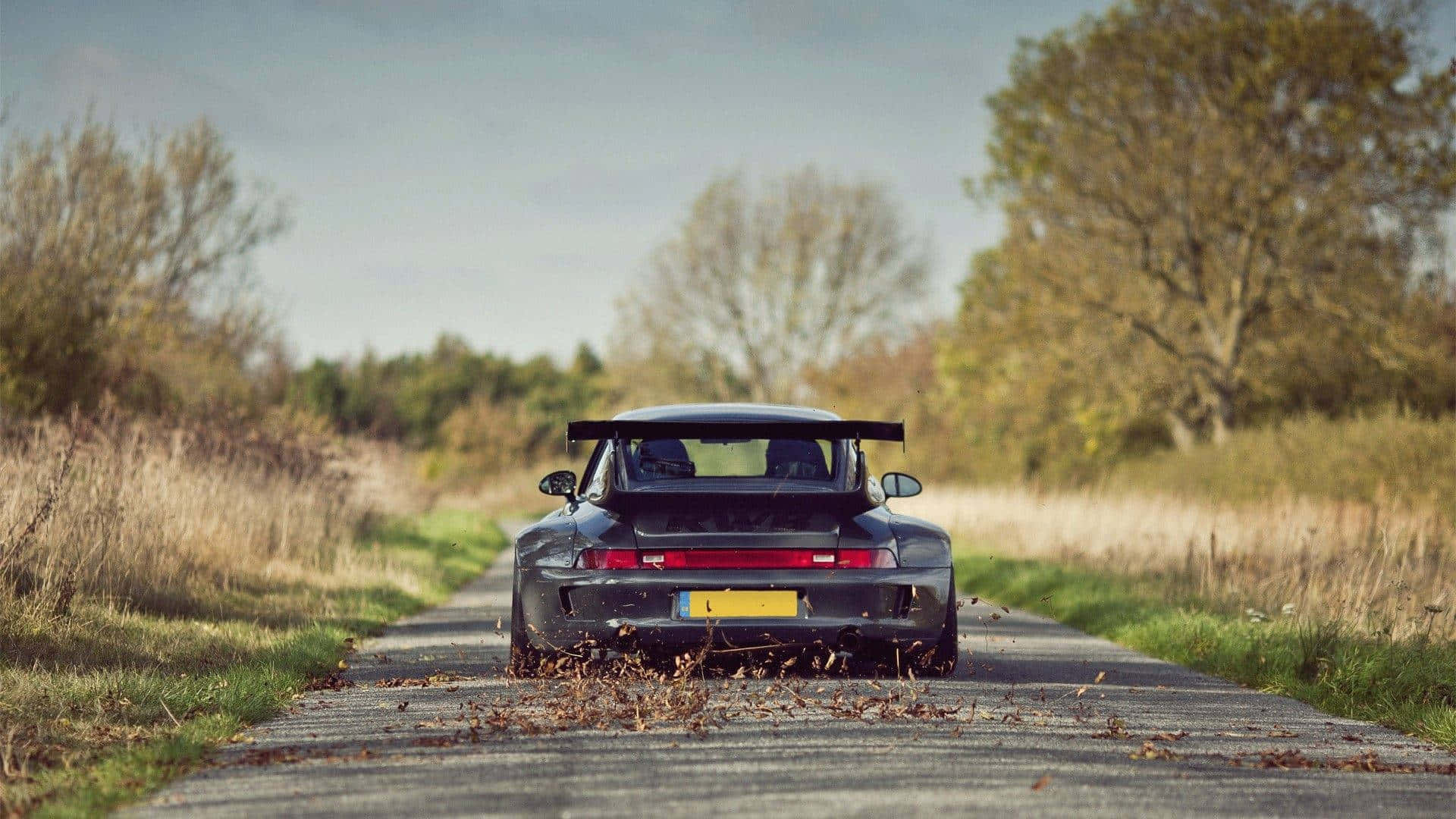 R W B Porsche On Country Road Background