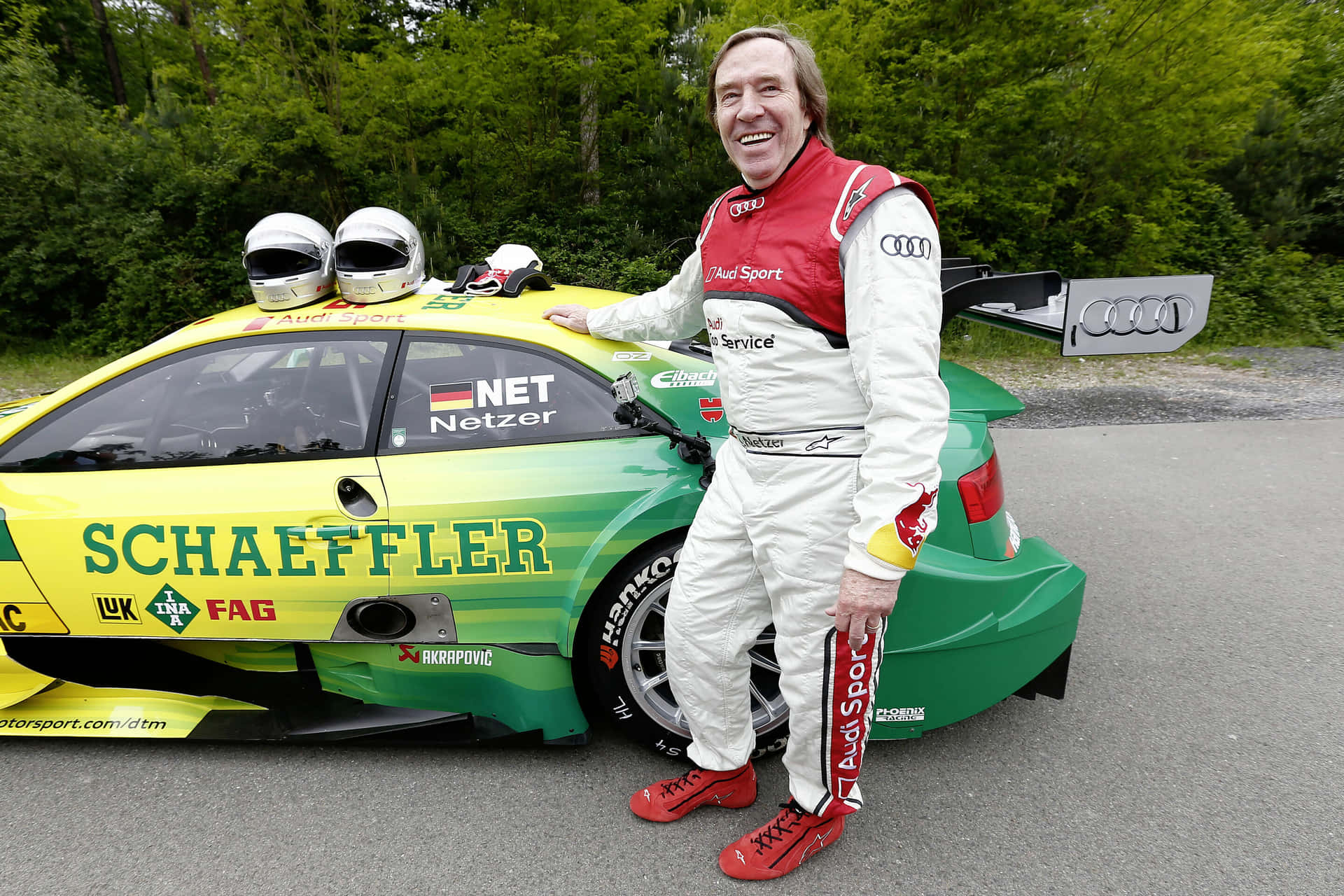 Racing Driver Smiling Beside Audi Race Car Background