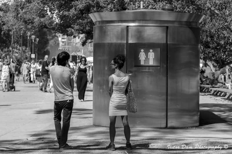 Random People Waiting Outside A Public Restroom Background