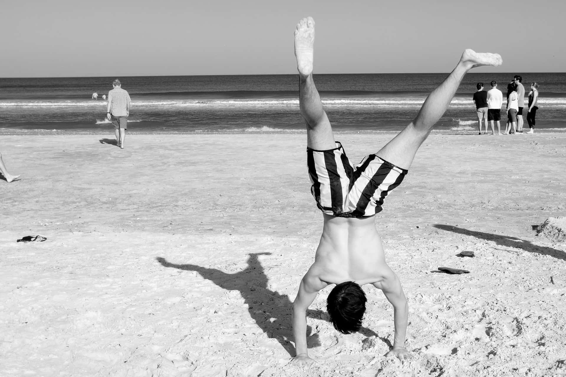 Random Person Performing Handstand On Beach Background