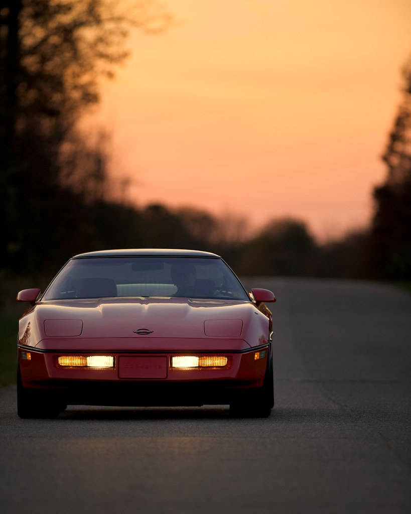 Red C4 Corvette Under The Sunset Background