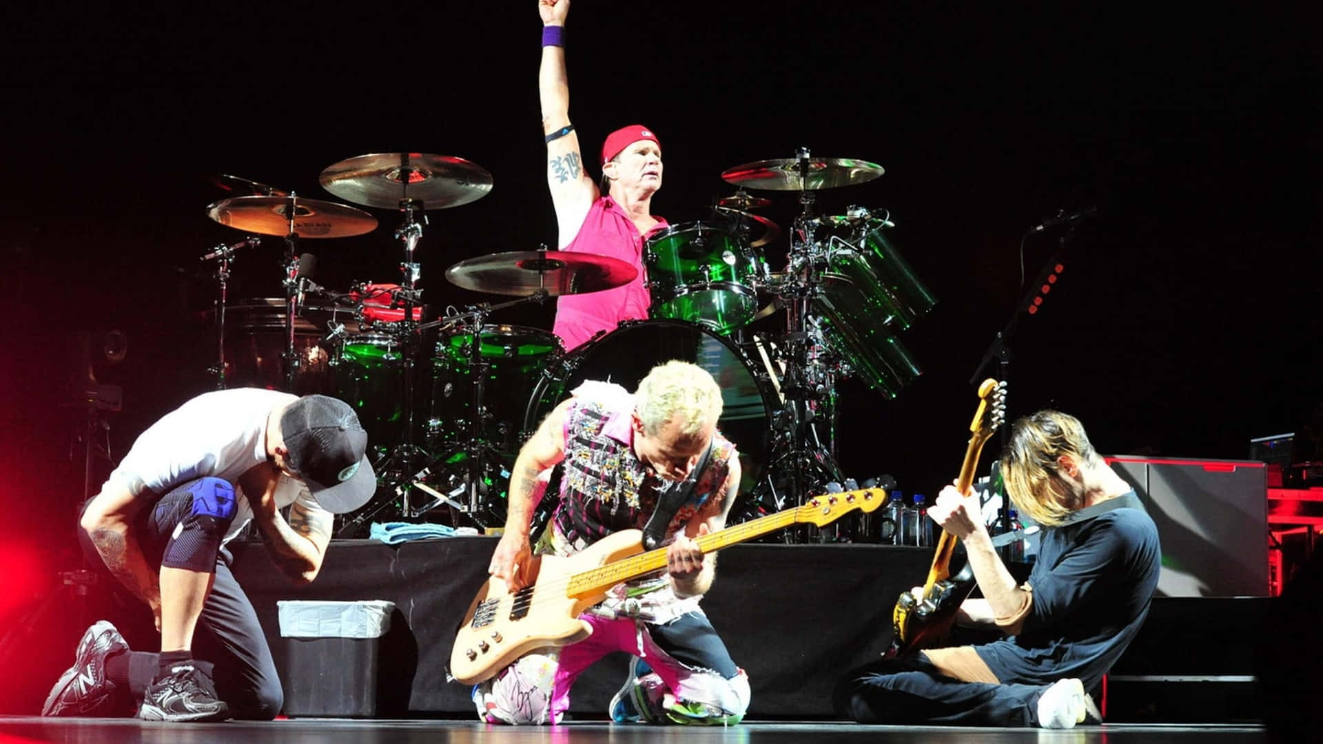 Red Hot Chili Peppers Kneeling On Stage Background