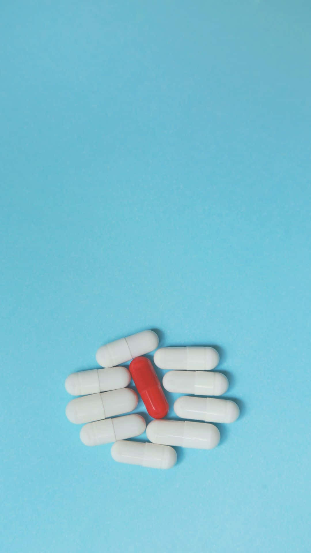 Red Pill Among White Capsuleson Blue Background