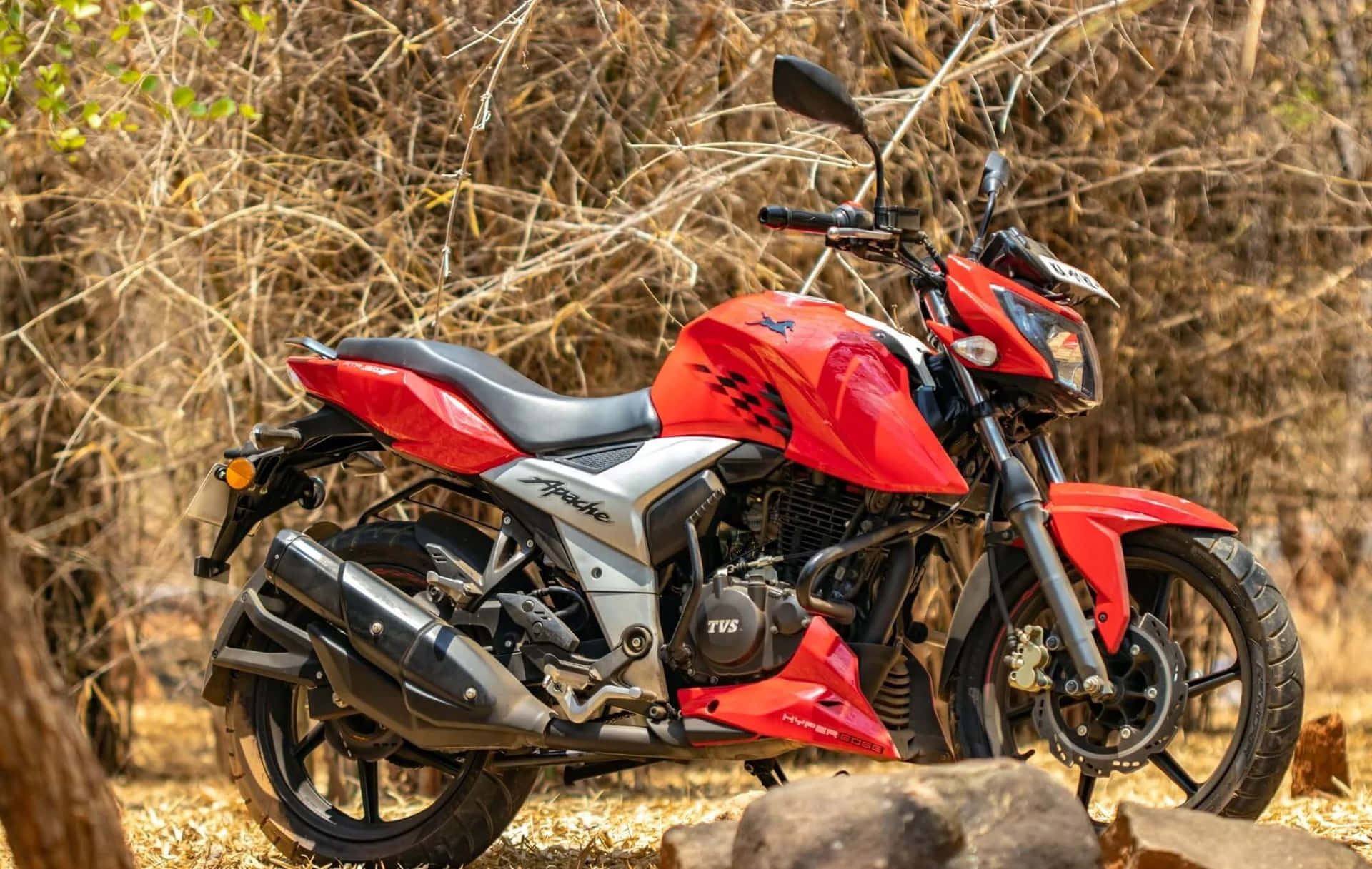 Red T V S Apache Motorcyclein Wilderness Background