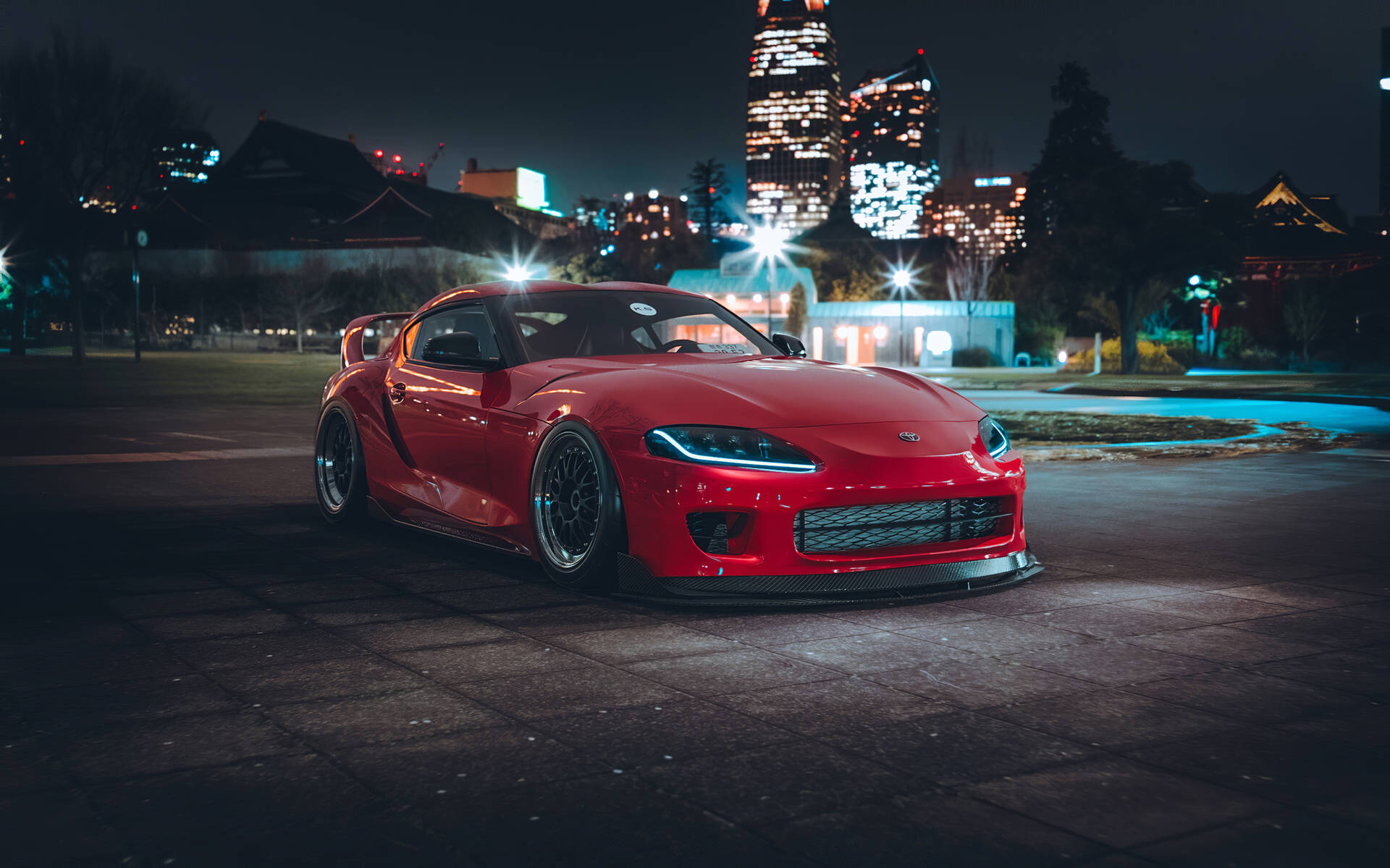 Red Toyota Supra Parked Near Cityscape Background