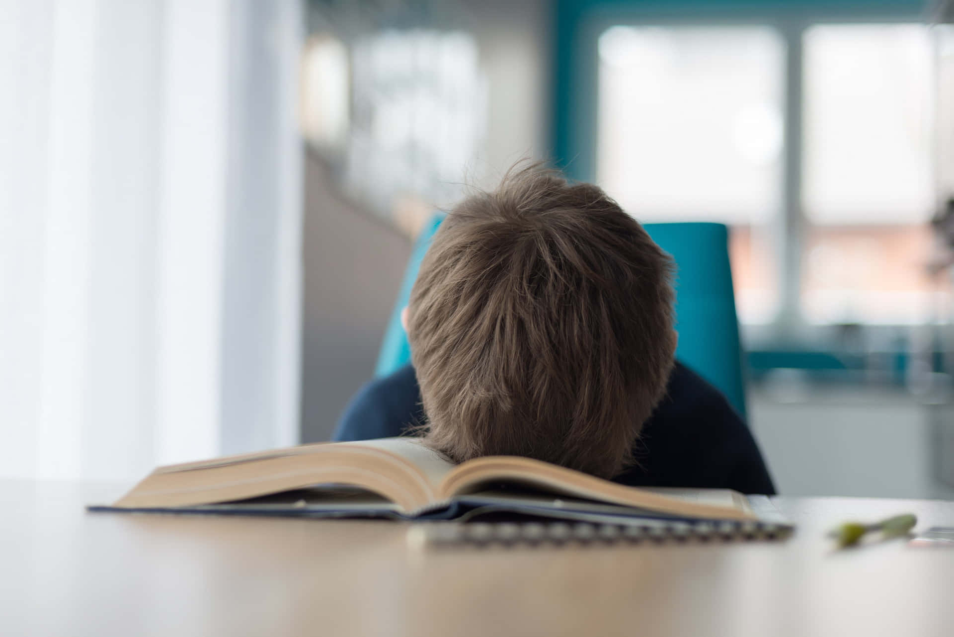 Reluctant Boy Sleeping On Book Background