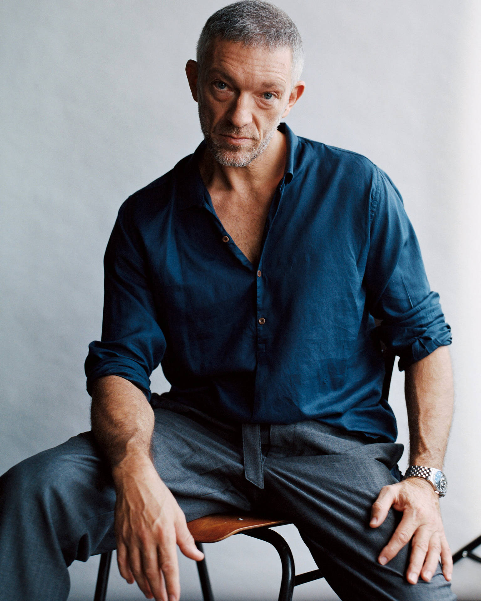 Renowned Actor Vincent Cassel Contemplatively Sitting On A Chair Background