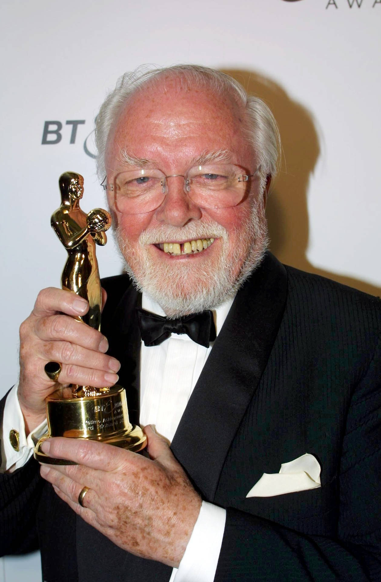 Richard Attenborough Holding A Golden Trophy Background